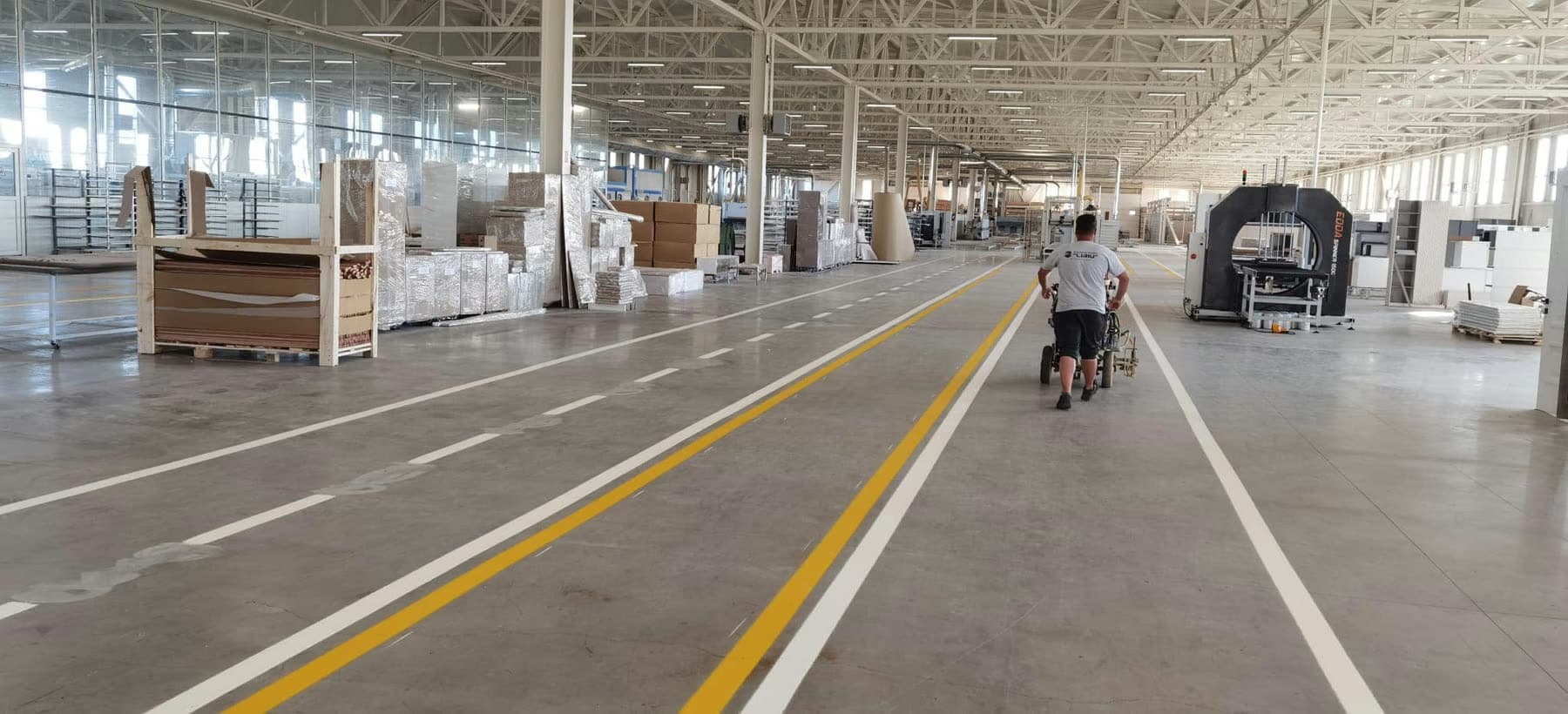Vijëzim i dyshemesë në një hapësirë industriale, me korsi të shënuara për lëvizje të brendshme